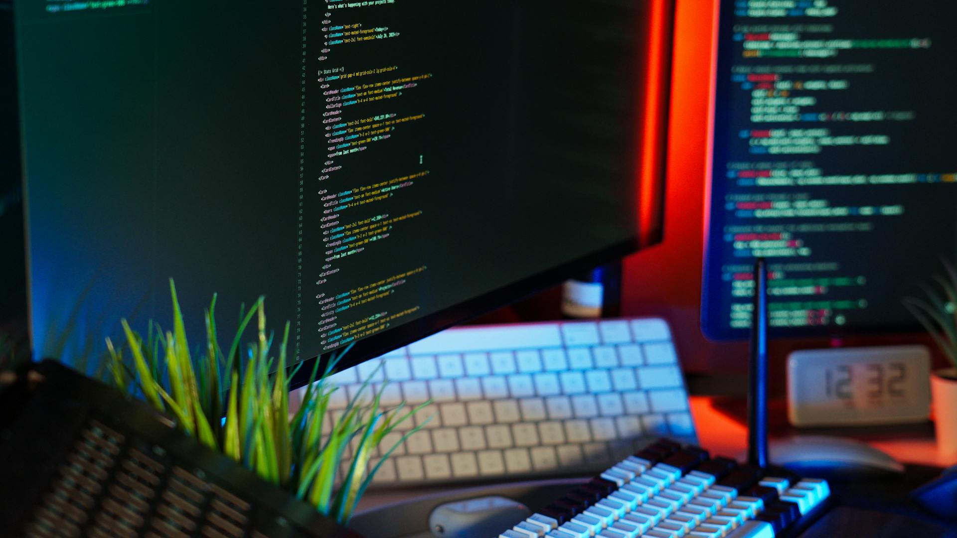 A vibrant workspace showing computer monitors with code, keyboard, and tech accessories