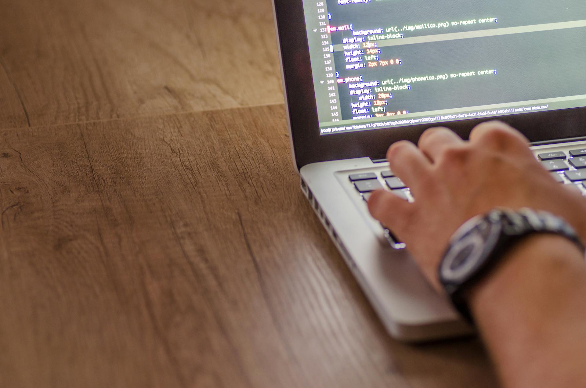 Close-up of a person coding on a laptop, showcasing web development and programming